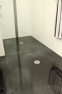 Another angle of the shower area, showing the metallic epoxy floor meeting the drain outlets seamlessly.